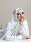 Woman wearing a white hijab and white blouse against a plain background