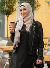 Woman holding a coffee cup outdoors, wearing a hijab and black outfit